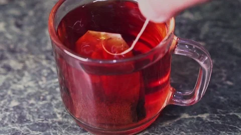 A teabag is dipped in a cup of tea and stirred Stock Footage 103123914