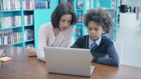Teacher and elementary student using laptop together Stock Footage 108746065