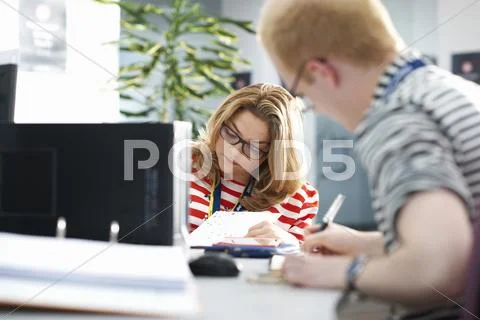 Teacher And Female Student Writing In Classroom Tutorial