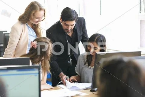 Teacher And Group Of Students Working In Computer Classroom