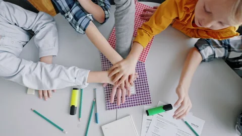 Teacher and pupils put hands in gesture of team unity Video stock 219963094