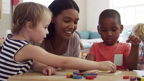 Teacher And Pupils Using Wooden Shapes In Montessori School Stock Footage