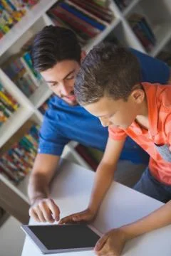 Teacher and school kid using digital table in library at school Foto stock