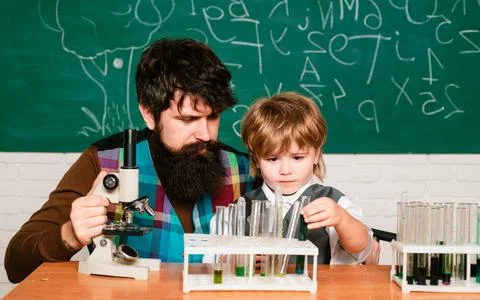 Teacher and schoolboy using microscope in class. Wunderkind. Science and Stock Photos