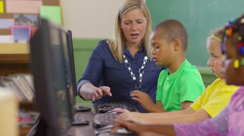 Teacher and student working on computers in school classroom Stock Footage