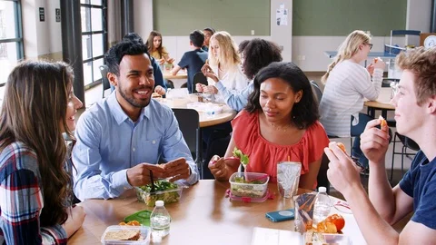 A group of cheerful small school kids in canteen, eating lunch and talking.  stock photo