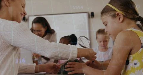 Teacher and students exploring model volcano at school table, with magnifying Stock Photos