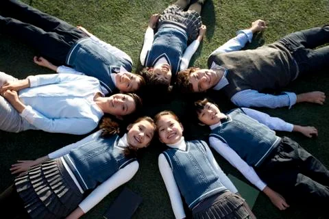Teacher and students lying in a circle on grass Stock Photos