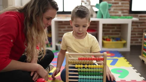 Teacher and toddler learning maths with abacus sitting on floor at kindergart Stock Footage 231503328