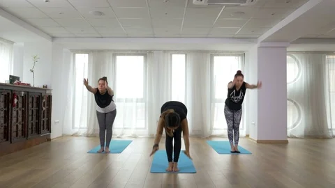 Teacher and two learners doing yoga sequence together during class Stock Footage 71788355