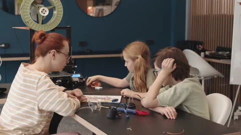 Teacher and Two Teenagers Constructing Robot in Workshop Video stock 153469415