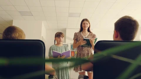 Teacher asks boy raising hand to change little girl at reading lesson Stock Footage 253254424