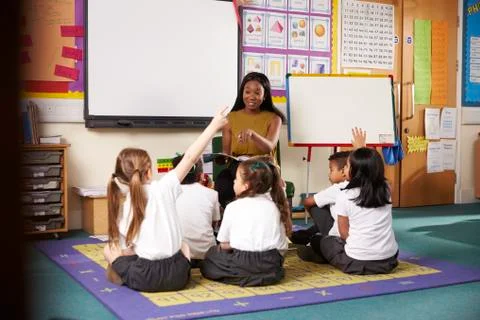 Teacher Asks Elementary School Pupils Question In Classroom Stock Photos