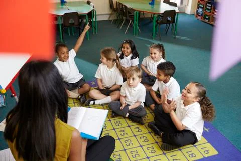 Teacher Asks Elementary School Pupils Question In Classroom Stock Photos