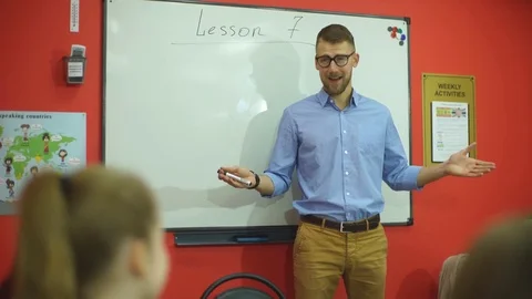 The teacher asks a question to the group of students standing at the blackboard Stock Footage 70579117