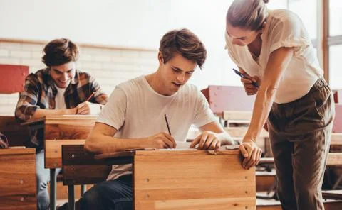 Teacher assisting the problem of a student in her classroom Stock Photos