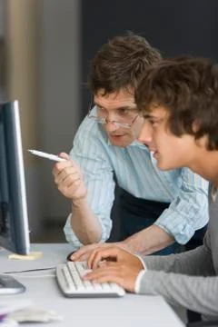 Teacher assisting student with computer assignment Stock Photos