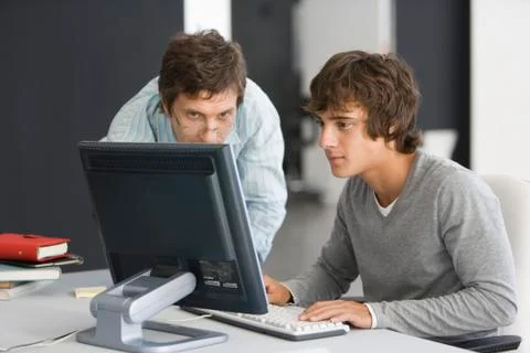 Teacher assisting student with computer assignment Stock Photos