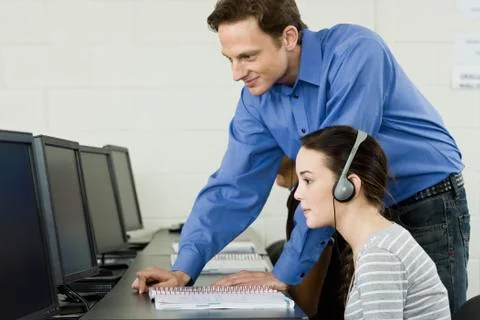 Teacher assisting student in computer lab Stock Photos