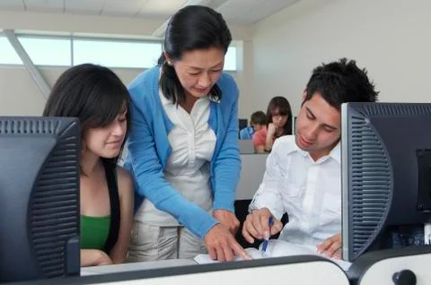 Teacher Assisting Students In Computer Lab Stock Photos
