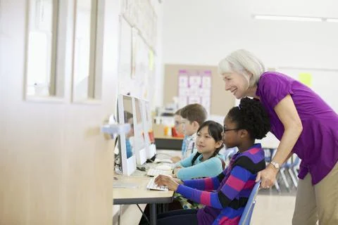 Teacher assisting students in computer lab Stock Photos