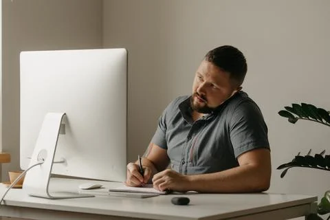 Teacher with a beard is preparing for an online lecture near a computer at ho Stock Photos