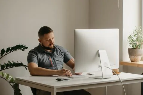 Teacher with a beard is preparing for an online lecture near a computer at ho Stock Photos