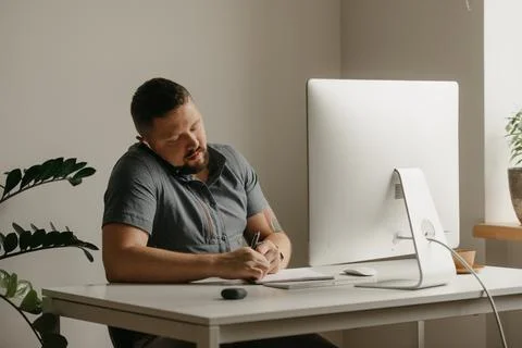 Teacher with a beard is preparing for an online lecture near a computer at ho Stock Photos