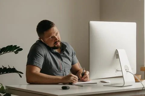 Teacher with a beard is preparing for an online lecture near a computer at ho Stock Photos