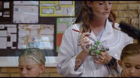 Teacher coming in holding model teaching science while class writing under faint Stock Footage 332981634