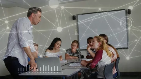 Teacher coming to table pointing to laptop using pad teaching students noting Stock Footage 334337969