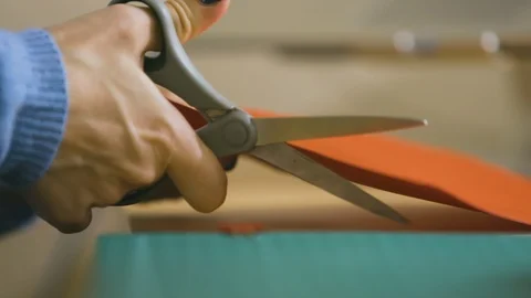 Teacher cutting red paper with scissors in slow motion Stock Footage 109423340