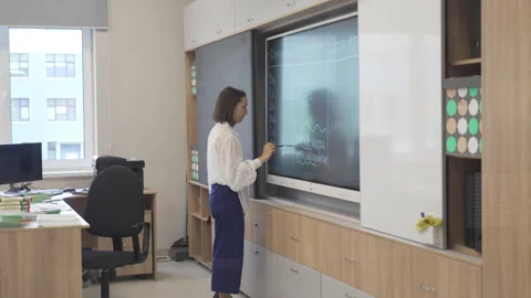 Teacher delivers lesson while writing formulas on blackboard Stock Footage 306416649
