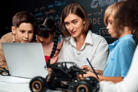 Teacher demonstrate attentive children to code robots in STEM class. Erudition. Stock Photos