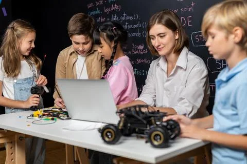 Teacher demonstrate attentive children to code robots in STEM class. Erudition. Stock Photos