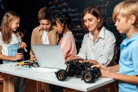 Teacher demonstrate attentive children to code robots in STEM class. Erudition. Stock Photos