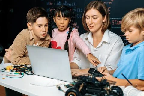 Teacher demonstrate attentive children to code robots in STEM class. Erudition. Stock Photos