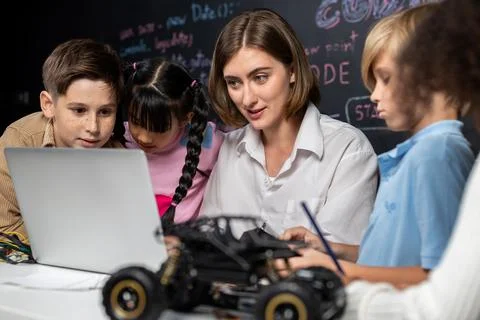 Teacher demonstrate attentive children to code robots in STEM class. Erudition. Stock Photos