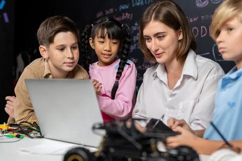 Teacher demonstrate attentive children to code robots in STEM class. Erudition. Stock Photos