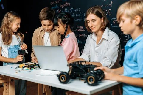 Teacher demonstrate attentive children to code robots in STEM class. Erudition. Stock Photos
