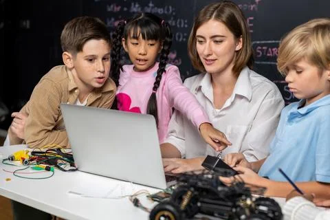 Teacher demonstrate attentive children to code robots in STEM class. Erudition. Stock Photos