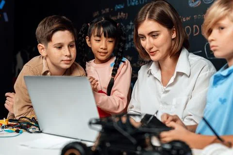 Teacher demonstrate attentive children to code robots in STEM class. Erudition. Stock Photos