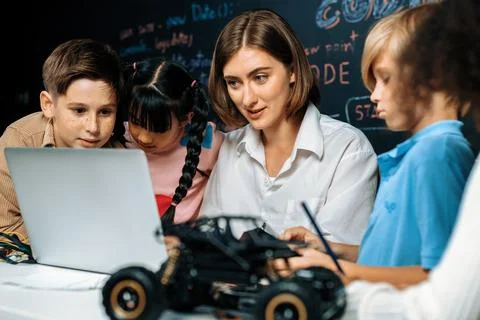 Teacher demonstrate attentive children to code robots in STEM class. Erudition. Stock Photos