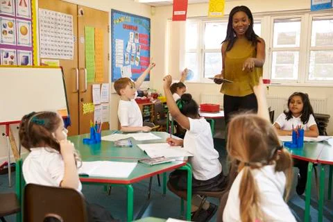 Teacher With Digital Tablet In Elementary School Classroom Stock Photos