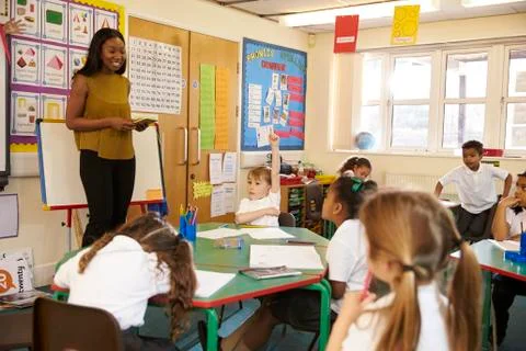 Teacher With Digital Tablet In Elementary School Classroom Stock Photos