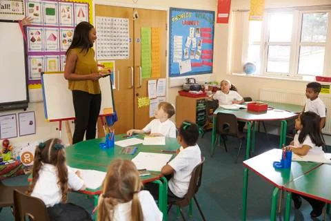 Teacher With Digital Tablet In Elementary School Classroom Stock Photos