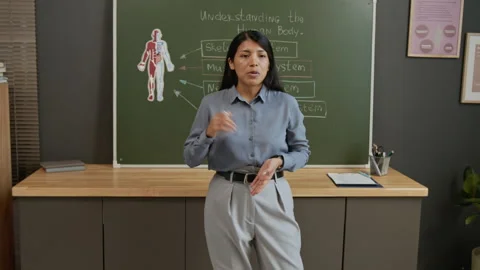 Teacher Drawing on Board while Talking about Human Body Systems to Students Stock Footage 333749687