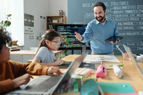 Teacher Engaging Students in Coding Lesson With Laptops Stockfoto's