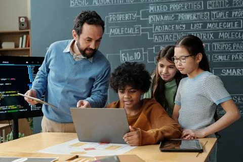 Teacher Engaging Students in Computer Class With Laptops Stock Photos