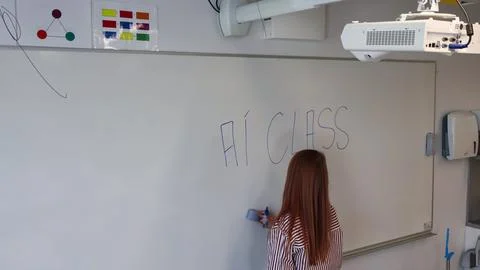 Teacher erasing AI CLASS on whiteboard in modern classroom Stock Photos